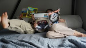 Two children reading Ranger Rick magazines on a bed