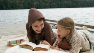 Two children read books on a dock